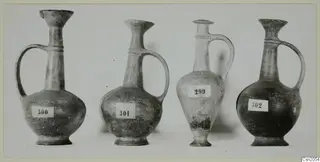 Four pottery Base Ring jugs with single handles, standing in a row with number labels