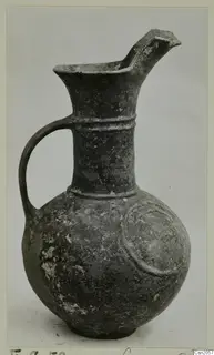Pottery Base-Ring Ware jug with a pinched spout, a loop handle and a raised arc motif on its body.