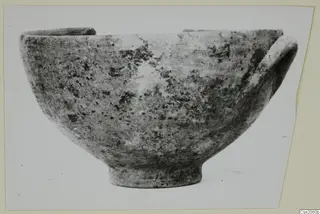 Bowl with a rounded body, ring foot and a handle on its right side, photographed against a pale background