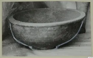 Bowl with a thick rim and rounded body, photographed on a pale surface, with blue lines tracing its outline