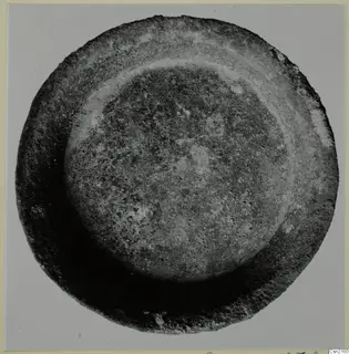 Shallow bowl seen from directly above, with a raised inner ridge and an encrusted surface