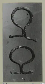 Two bronze loop-shaped mountings or handles from Marion, photographed on a grey background