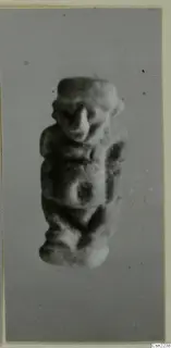 Small modelled figurine of a human figure with a broad head and prominent nose, shown alone