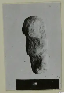 Rough stone object with a rounded upper part, shown upright on a card mount