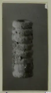 Blurred close view of a cylindrical object with horizontal ridges against a dark grey backdrop