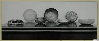 Several blown glass bowls and dishes standing in a row on a dark table
