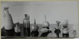 Group of blown glass jugs, jars and flasks with handles on a dark table