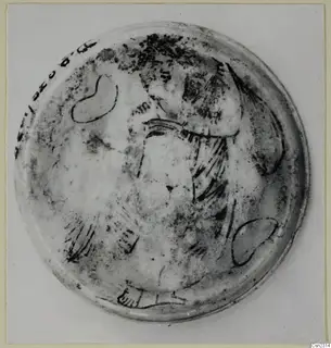 Shallow circular glass object seen from above, with dark painted lines forming a pattern across its surface
