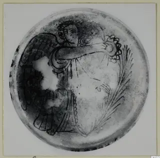 Blown glass object seen from above, decorated with dark painted lines of a winged figure and feathery fronds