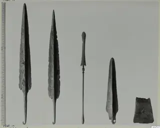 Five metal implements laid in a row after conservation, with a graduated scale ruler along the left edge.
