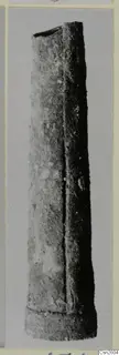 Bronze weapon: a long, tapering tubular metal object with an open top, photographed upright against a plain background