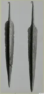Two long metal blades with curled hooked tangs, set side by side against a plain grey background.