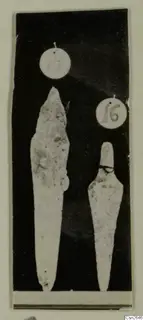 Two pale weapon-shaped objects with round number labels above them, photographed against a dark background