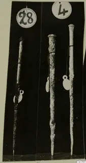 Three long corroded metal tools with pointed tips, photographed upright against a black background