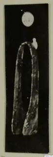 Bronze tool with two long arms joined by a rounded bend, photographed against a black background