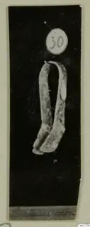 Bronze tool: a bent metal object with two arms joined at the top, photographed against black with a number label above it.