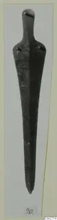 Long tapered bronze tool with a rounded top and two rivet holes at the shoulders