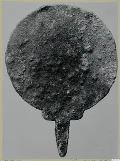 Corroded bronze disc with a tapering tang, one of the toilet requisites from the Marion tombs