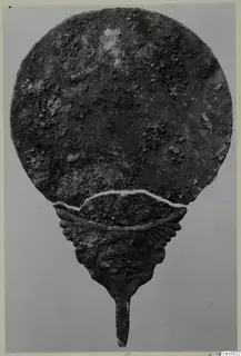 Bronze mirror from Marion with a round, corroded disc and a handle topped by a face in relief