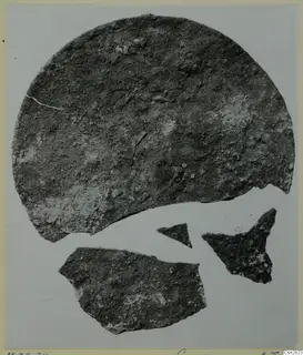 Corroded metal disc with three smaller fragments on a pale background, Marion finds