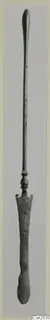Bronze toilet implement with a long slender shaft and a flat spatula-like end, shown upright