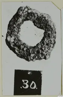 Corroded bronze ring-shaped object with a large central hole, shown with a number label below it
