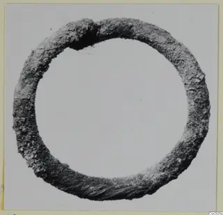 Corroded bronze ring photographed against a plain pale background