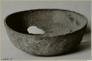 Rounded bowl with a wide open mouth and a hole broken through one side of its wall.