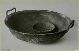 Large corroded metal bowl with two loop handles, with a small dish nested inside it