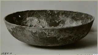 Bowl before conservation, with a crusty encrusted surface and a broken hole in the inner wall.
