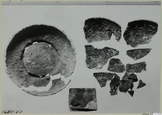 Shallow dish with broken rim beside a scatter of pottery sherds, shown before conservation
