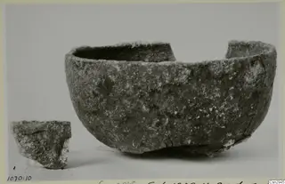 A large rough-surfaced bowl with a broken rim and a separate sherd beside it