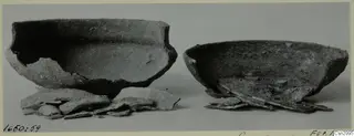 Two broken bowls with loose sherds in front, photographed before conservation