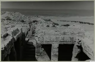 Excavated rock-cut structure with two doorways and a stepped passage, with the sea beyond