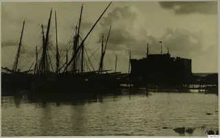Paphos Castle silhouetted behind a row of sailing boats moored in the harbour at Paphos