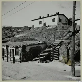 Wooden staircase climbing a hillside past low buildings at Skouriotissa