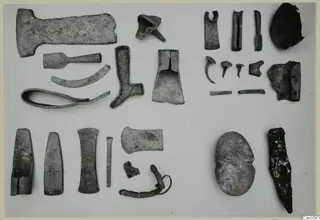 Various corroded metal tools and fragments from Mathiati laid out in rows on a pale surface