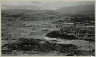 View over Skouriotissa from Foukassa Hill, with dark slag heaps in the foreground and a valley and mountains beyond