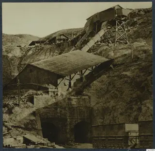 Skouriotissa copper mine: sheds, a sloping chute and arched tunnel entrances on a steep, bare hillside.