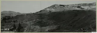 Dark slag heap on the slope of Foukassa Hill at Skouriotissa, with a winding road and small figures below