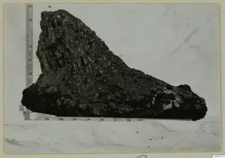 Dark, knobbly lump of material photographed beside a measuring ruler, from the copper mining series