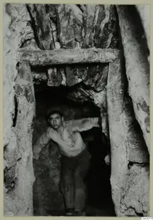Underground passage at Mavrovouni with timber beam and posts, and a young man standing in the opening
