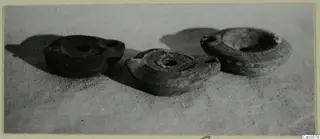 Three small lamps with nozzles and central filling holes resting on a textured cloth