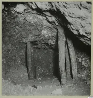 Ancient open stope at Mavrovouni, with wooden props holding up the rock and loose stones on the floor.