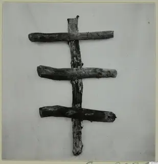 Ancient timber set: an upright post with three horizontal pieces across it, photographed against a pale background.