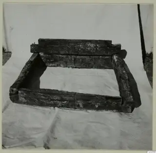 Ancient wooden crib-timbers forming a frame, set on a light cloth in front of a tent.