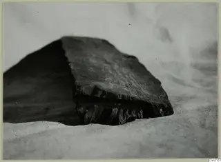 Dark wooden block with a split, broken end, resting on a pale cloth
