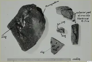 Fragments of stone and fired clay with handwritten labels and a centimetre ruler along the bottom edge.