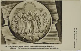 Printed card reproduction of a round silver relief disc showing five standing figures, two of them playing pipes, under an arched frame