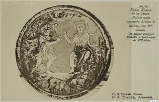 Round silver disc with raised relief figures and animals, photographed on a printed card mount